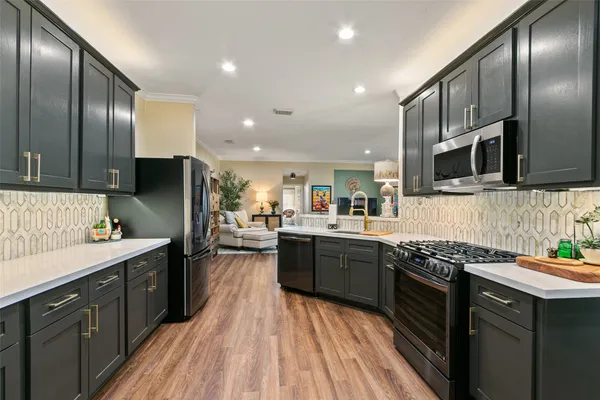 a kitchen with stainless steel appliances granite countertop refrigerator a sink a stove top oven and wooden floors