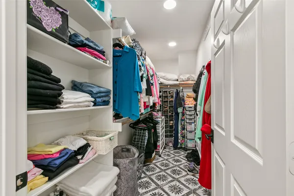 a view of walk in closet with clothes and shoes