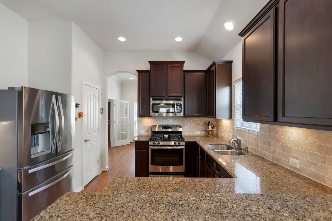3214 Clover Trace Drive Spring, TX 77386 - Photo 16 of 48 a kitchen with granite countertop stainless steel appliances a refrigerator and a stove top oven