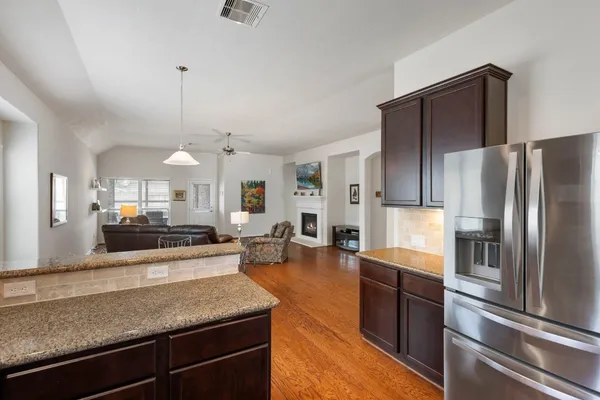 a kitchen with stainless steel appliances granite countertop a refrigerator a sink dishwasher a stove and white cabinets with wooden floor