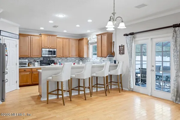 a kitchen with stainless steel appliances kitchen island granite countertop a stove a refrigerator a oven a sink with a dining table and chairs
