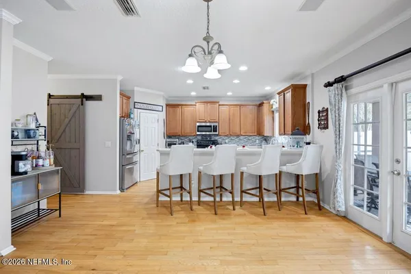 a large kitchen with stainless steel appliances kitchen island granite countertop a refrigerator a stove a dining table and chairs with wooden floor