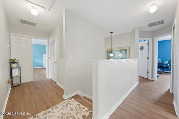 a view of a hallway to a livingroom with wooden floor and a cabinet