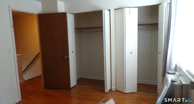 a view of an empty room with wooden floor and a bathroom