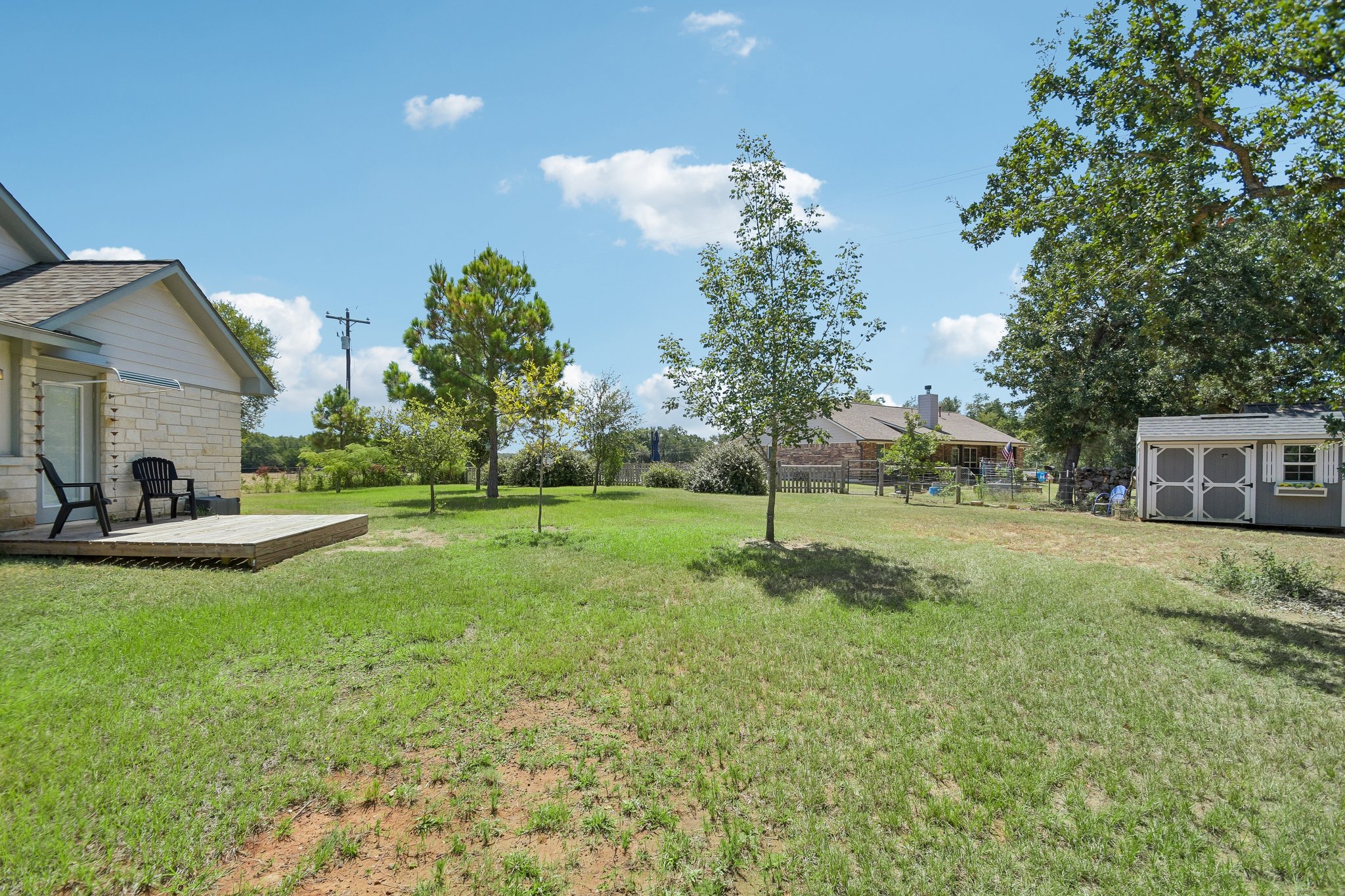 596 Pleasant Grove Loop Elgin, TX 78621 - Photo 33 of 37 A spacious green lawn sits under open skies with mature trees and a detached shed.