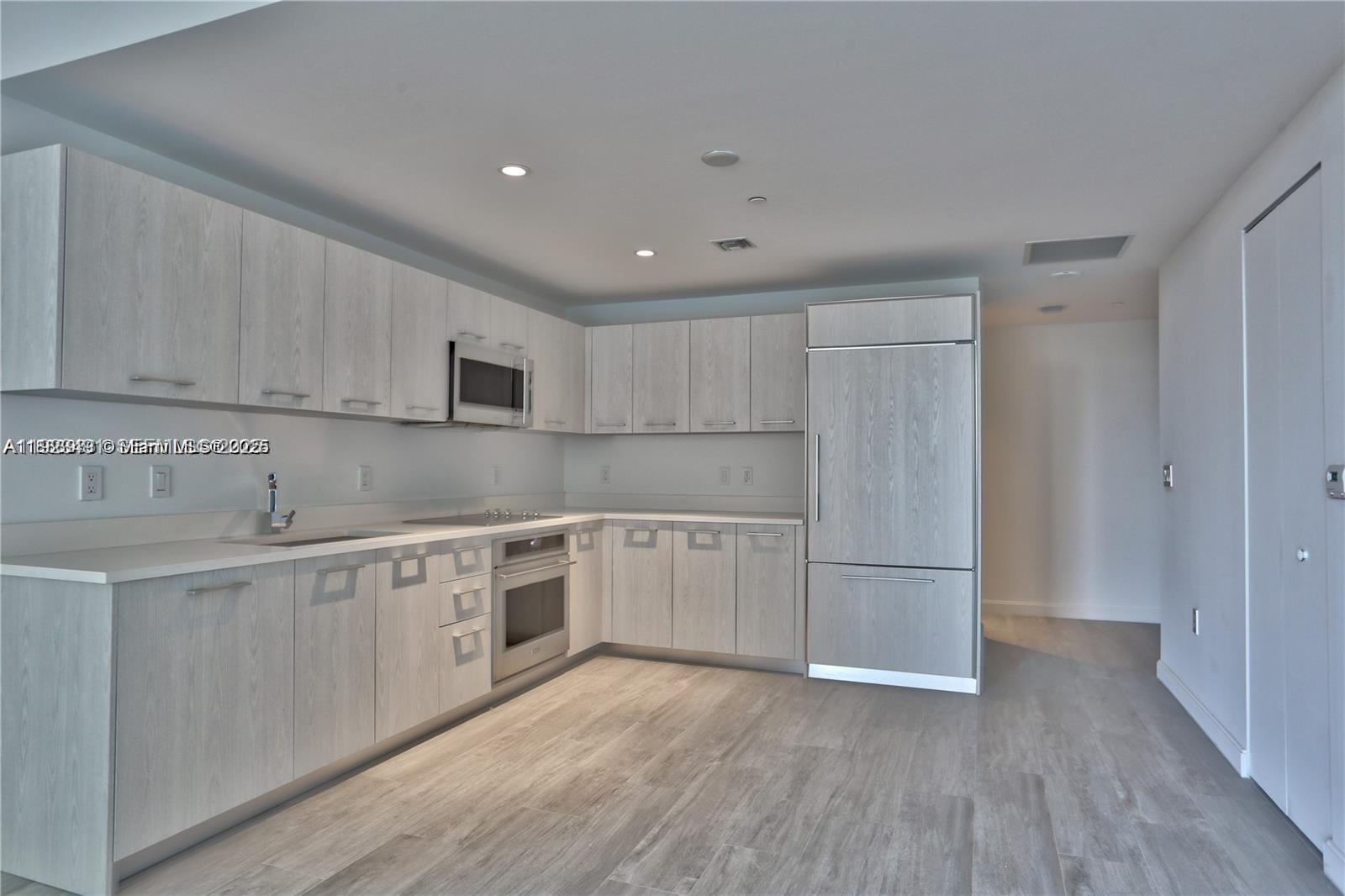 55 Southwest 9th Street, Unit 1910 Miami, FL 33130 - Photo 3 of 11 a kitchen with white cabinets and white appliances