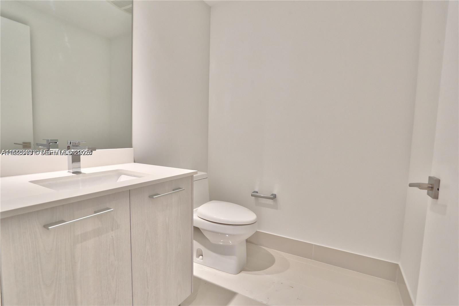 55 Southwest 9th Street, Unit 1910 Miami, FL 33130 - Photo 6 of 11 a bathroom with a sink a toilet and a mirror
