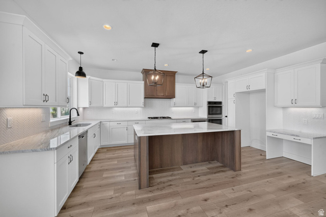 1002 West Temple Rim Lane Payson, UT 84651 - Photo 17 of 68 Spacious kitchen featuring an expansive island with a stone-finish countertop, white cabinetry, wood-finish flooring, and built-in double ovens