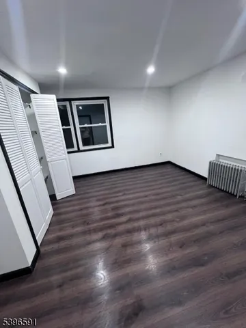 a view of an empty room with wooden floor and stairs