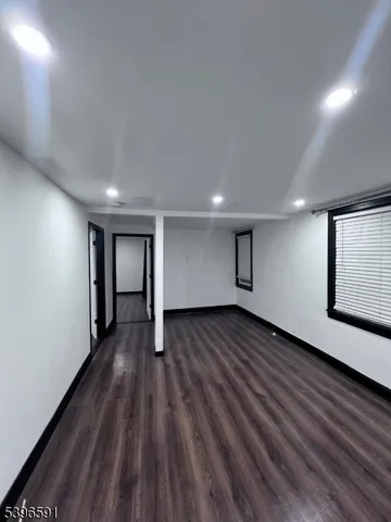 a view of an empty room with wooden floor and windows