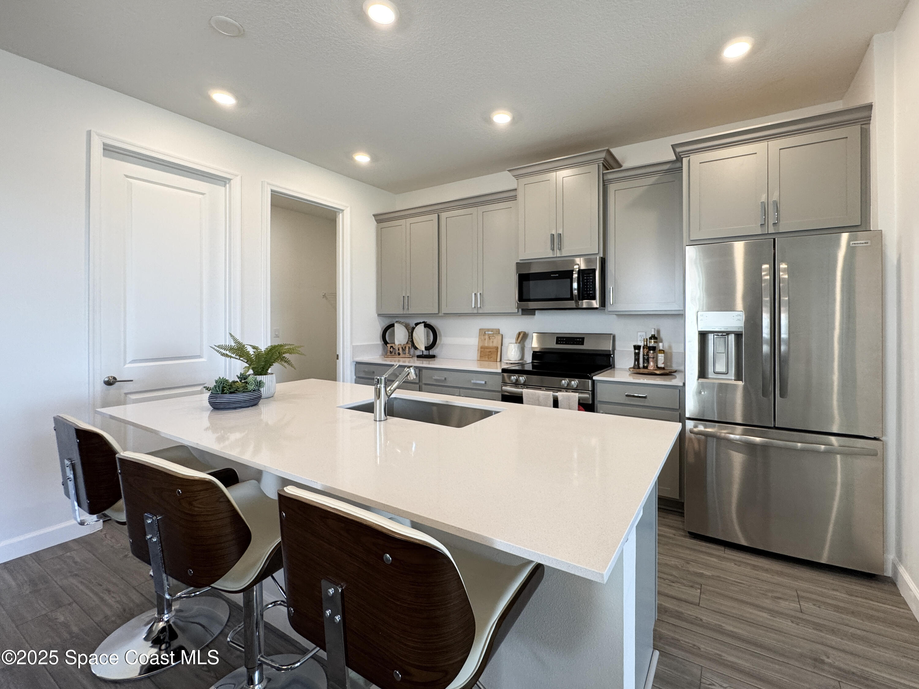 1959 Croft Inlet Drive Palm Bay, FL 32907 - Photo 2 of 23 a kitchen with kitchen island a stove a sink a microwave a refrigerator and white cabinets