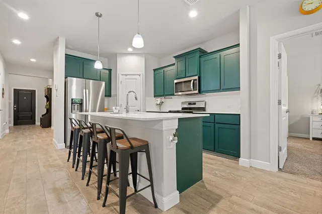 a kitchen with kitchen island granite countertop a sink a stove a refrigerator and a dining table with wooden floor