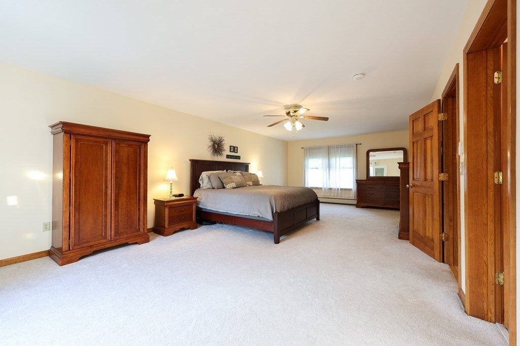 218 Lower Gore Road Webster, MA 01570 - Photo 16 of 40 a spacious bedroom with a bed and a chandelier