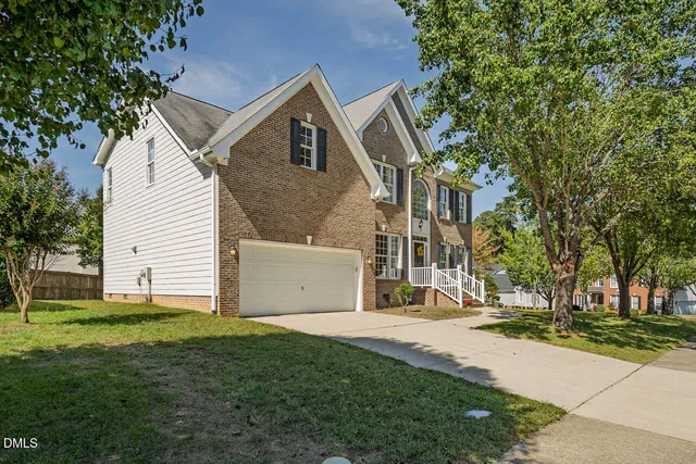 a view of a white house next to a yard with big trees