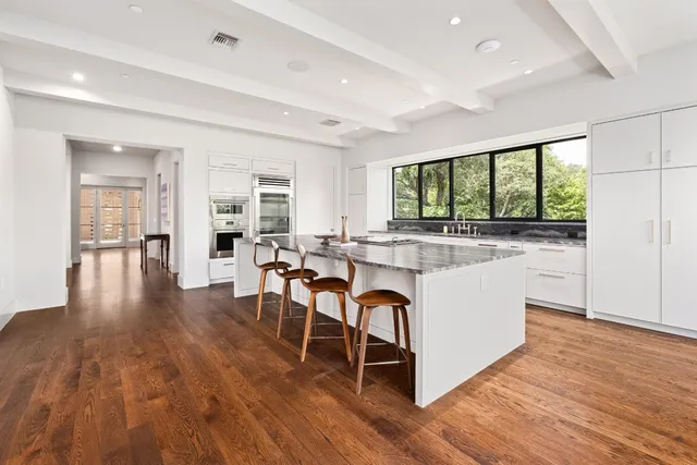 a kitchen with stainless steel appliances granite countertop wooden floors and white cabinets