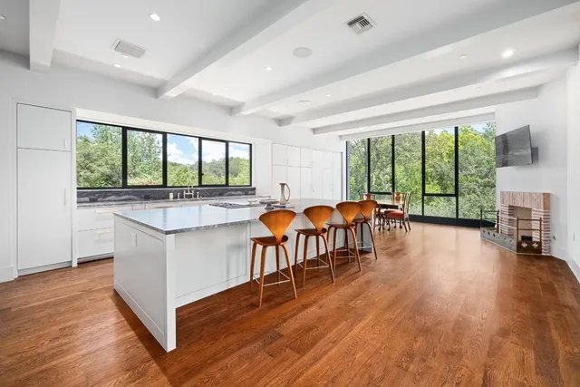 a open kitchen with stainless steel appliances granite countertop a large island a stove a table and chairs with wooden floor