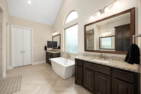 a spacious bathroom with a double vanity sink a mirror and a bathtub