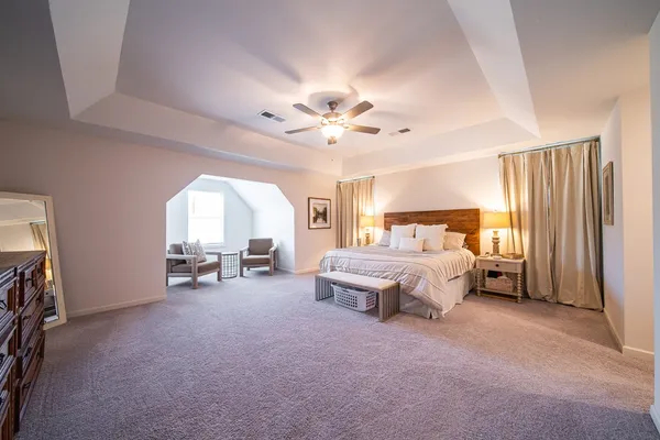 a spacious bedroom with a bed and a chandelier