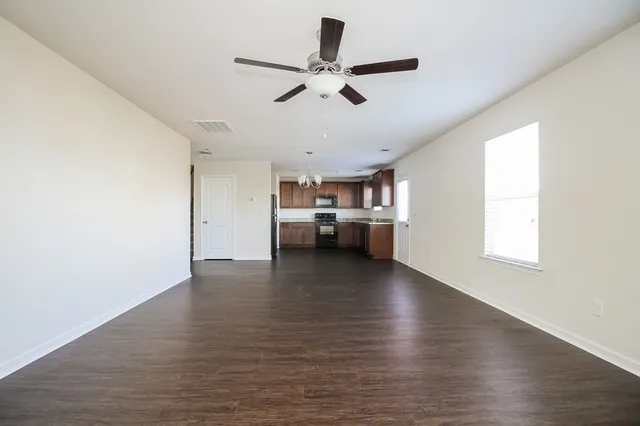 a view of empty room with wooden floor and window