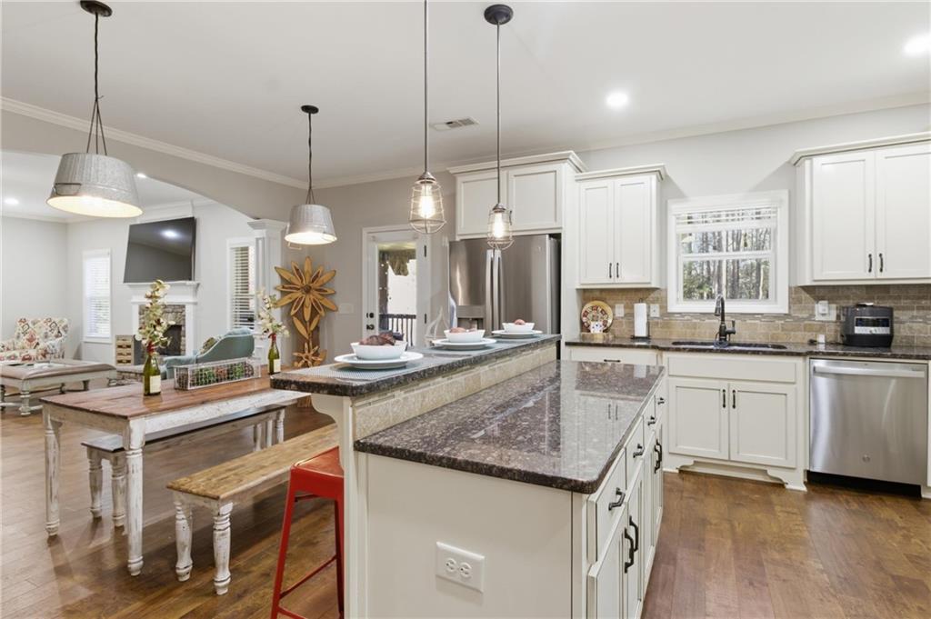 37 Farmstead Way Senoia, GA 30276 - Photo 43 of 121 a kitchen with kitchen island granite countertop a stove a sink a center island and a wooden floor