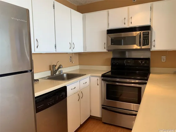 a kitchen with stainless steel appliances granite countertop white cabinets a stove a microwave and a refrigerator