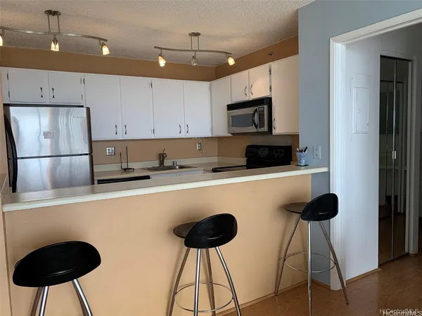 a kitchen with stainless steel appliances granite countertop a stove a refrigerator a sink a microwave and a dining table with wooden floor