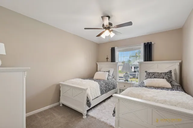 a bedroom with two beds and ceiling fan