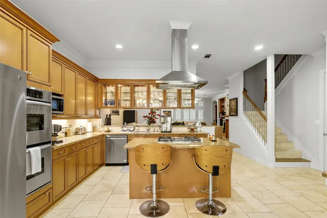 a kitchen with stainless steel appliances granite countertop a refrigerator a sink dishwasher a stove and a dining table with wooden floor