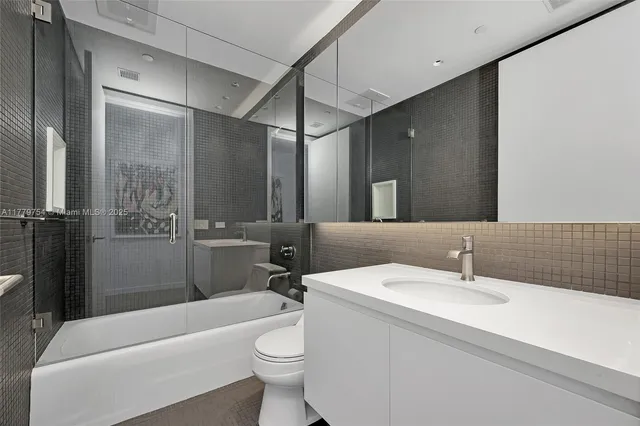 a bathroom with a toilet a sink a tub and mirror