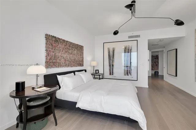 a spacious bedroom with a bed and a lamp on table