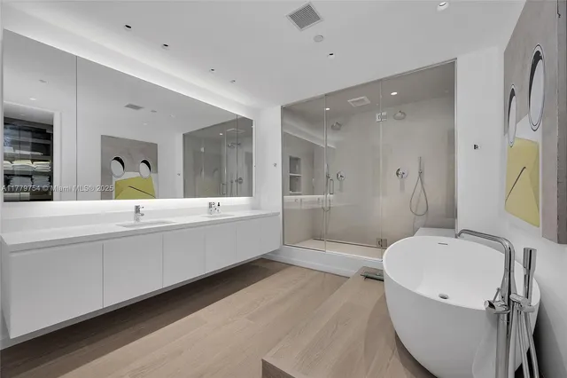 a bathroom with a tub double vanity sink and a large mirror