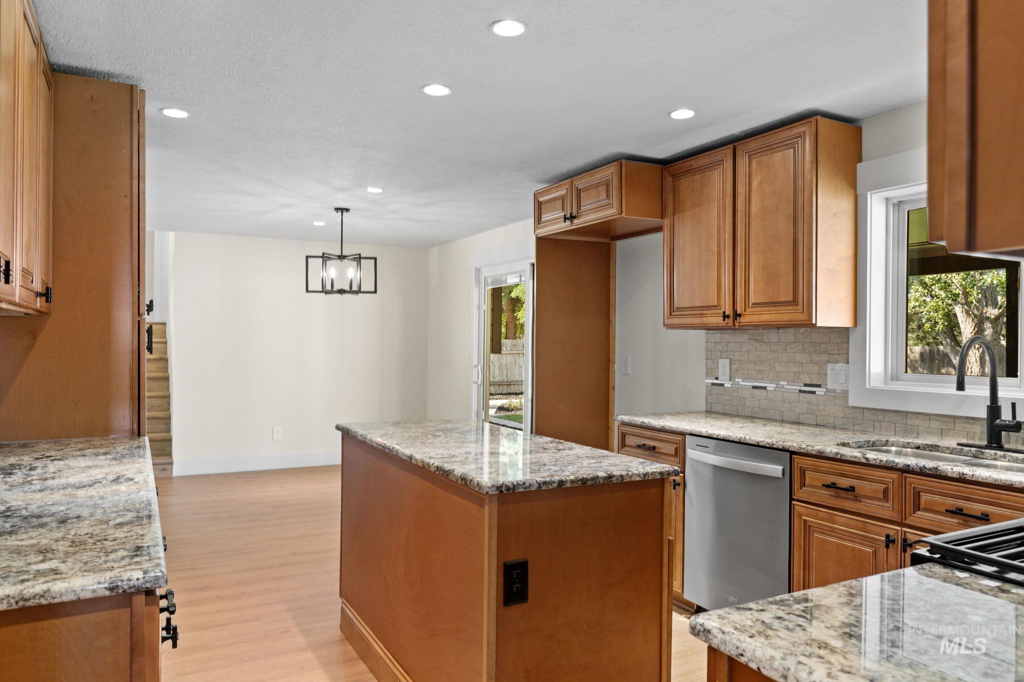1675 Country Terrace Way Meridian, ID 83642 - Photo 13 of 50 Kitchen featuring wood-finish cabinetry, granite countertops, stainless steel dishwasher, and tile backsplash