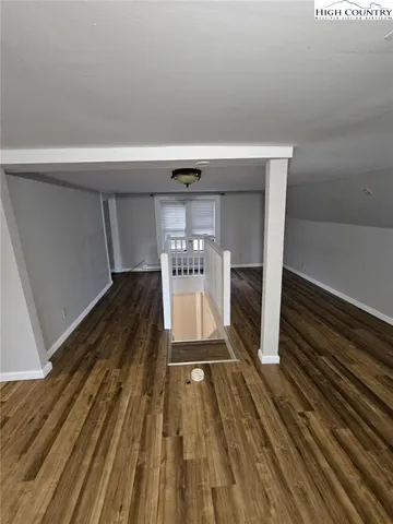 a hallway view with wooden floor and staircase