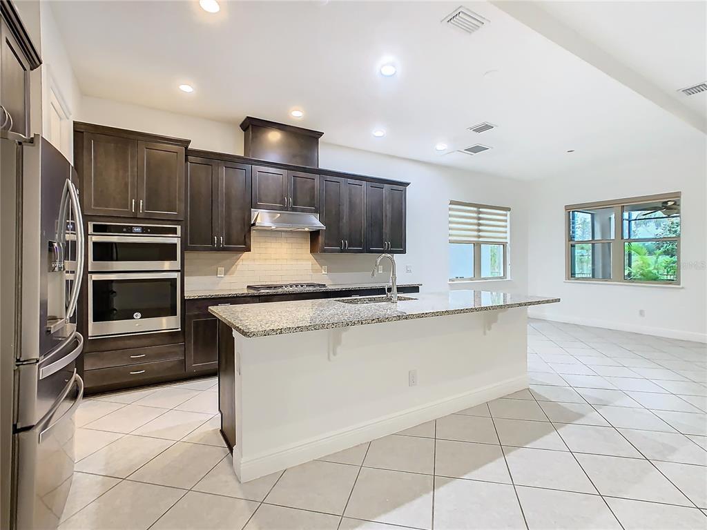 8325 Topsail Place Winter Garden, FL 34787 - Photo 12 of 74 a kitchen with kitchen island granite countertop a stove a sink and a refrigerator