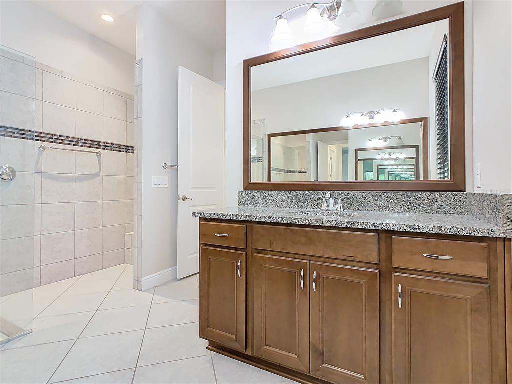 8325 Topsail Place Winter Garden, FL 34787 - Photo 35 of 74 a bathroom with a granite countertop sink a mirror and shower