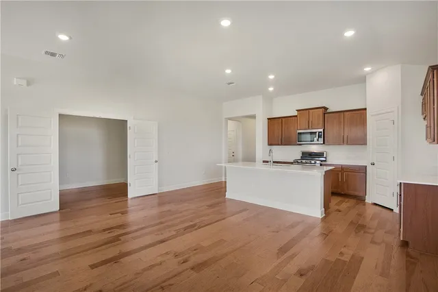 a large kitchen with kitchen island a sink wooden floor and stainless steel appliances