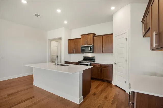 a kitchen with a sink a stove top oven and wooden floor