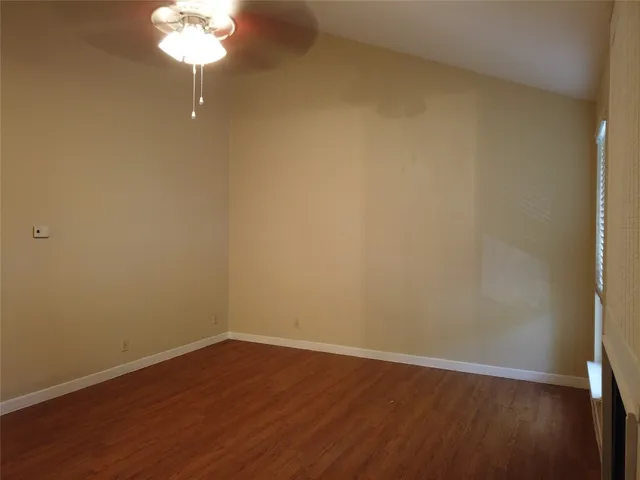 a view of a room with wooden floor and a fan