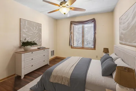 an empty room with wooden floor fan and windows
