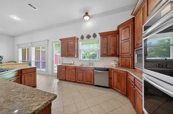 a large kitchen with kitchen island granite countertop wooden cabinets a granite counter tops and a sink