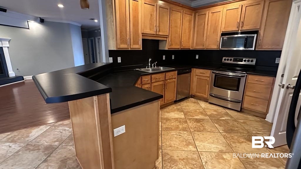 23289 McPhillips Road Loxley, AL 36551 - Photo 6 of 19 Kitchen featuring warm wood cabinetry, dark countertops, and stainless steel appliances