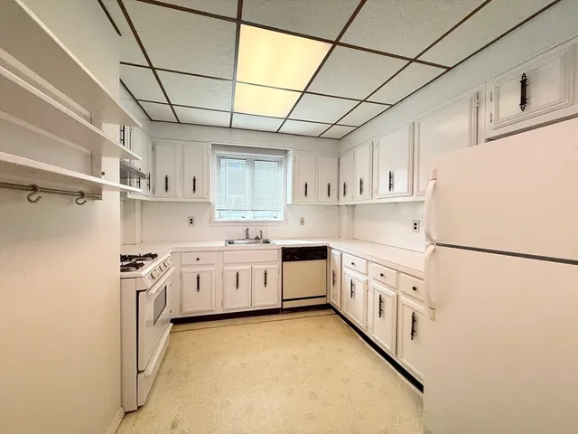 a kitchen with white cabinets and white appliances