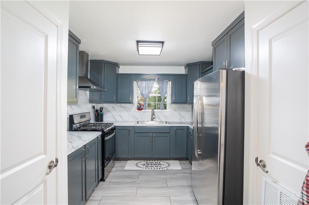 32516 El Preseno Road San Benito, TX 78586 - Photo 28 of 45 a kitchen with stainless steel appliances granite countertop a sink stove and refrigerator