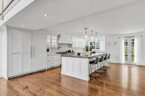 a kitchen with stainless steel appliances a white stove top oven cabinets and a wooden floor