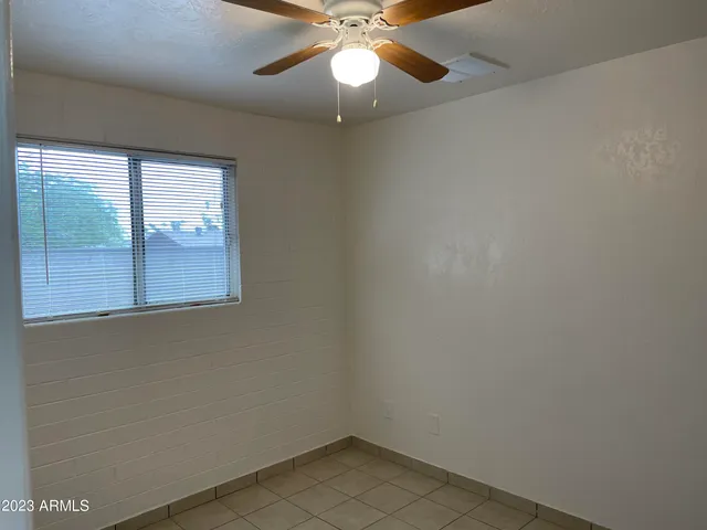 an empty room with a window and a fan
