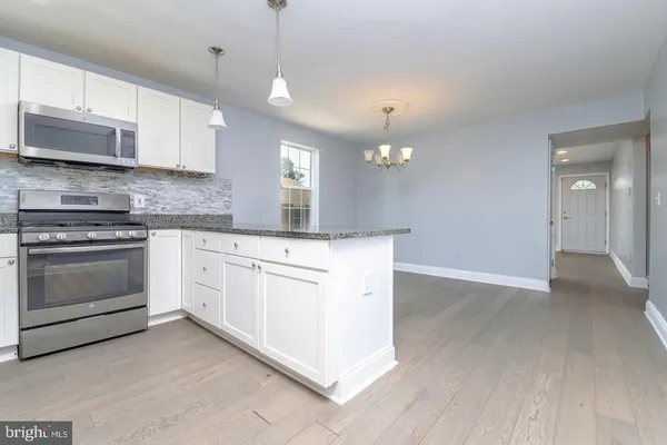 a kitchen with cabinets wooden floor and stainless steel appliances