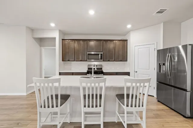 a kitchen with stainless steel appliances granite countertop a refrigerator and a stove top oven
