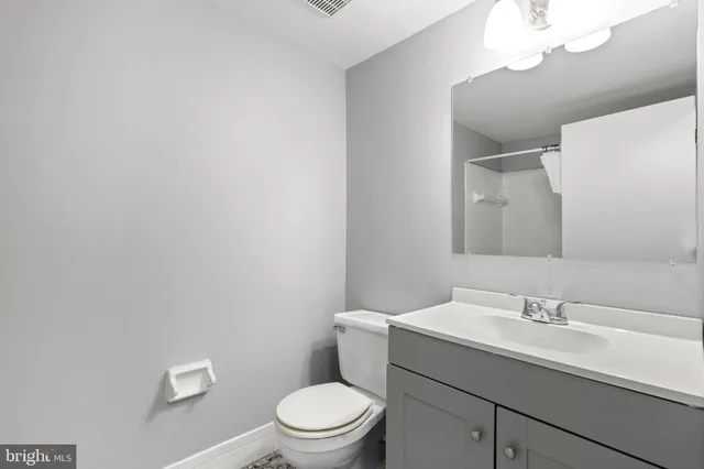 a bathroom with a toilet a sink a mirror and vanity