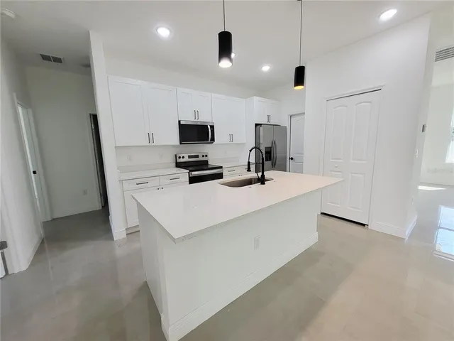 a kitchen with kitchen island white cabinets and refrigerator