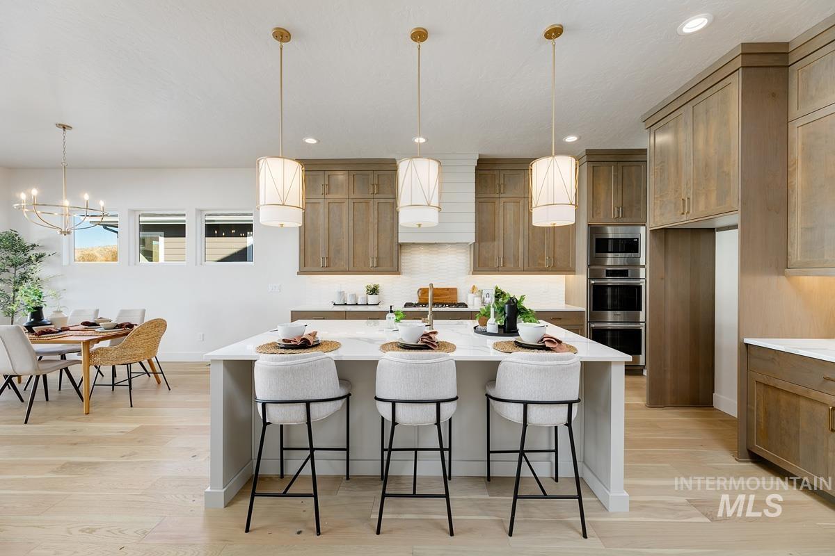 5817 South Gustav Avenue Meridian, ID 83642 - Photo 6 of 33 Spacious kitchen island with a white countertop and seating for three, complemented by three pendant lights